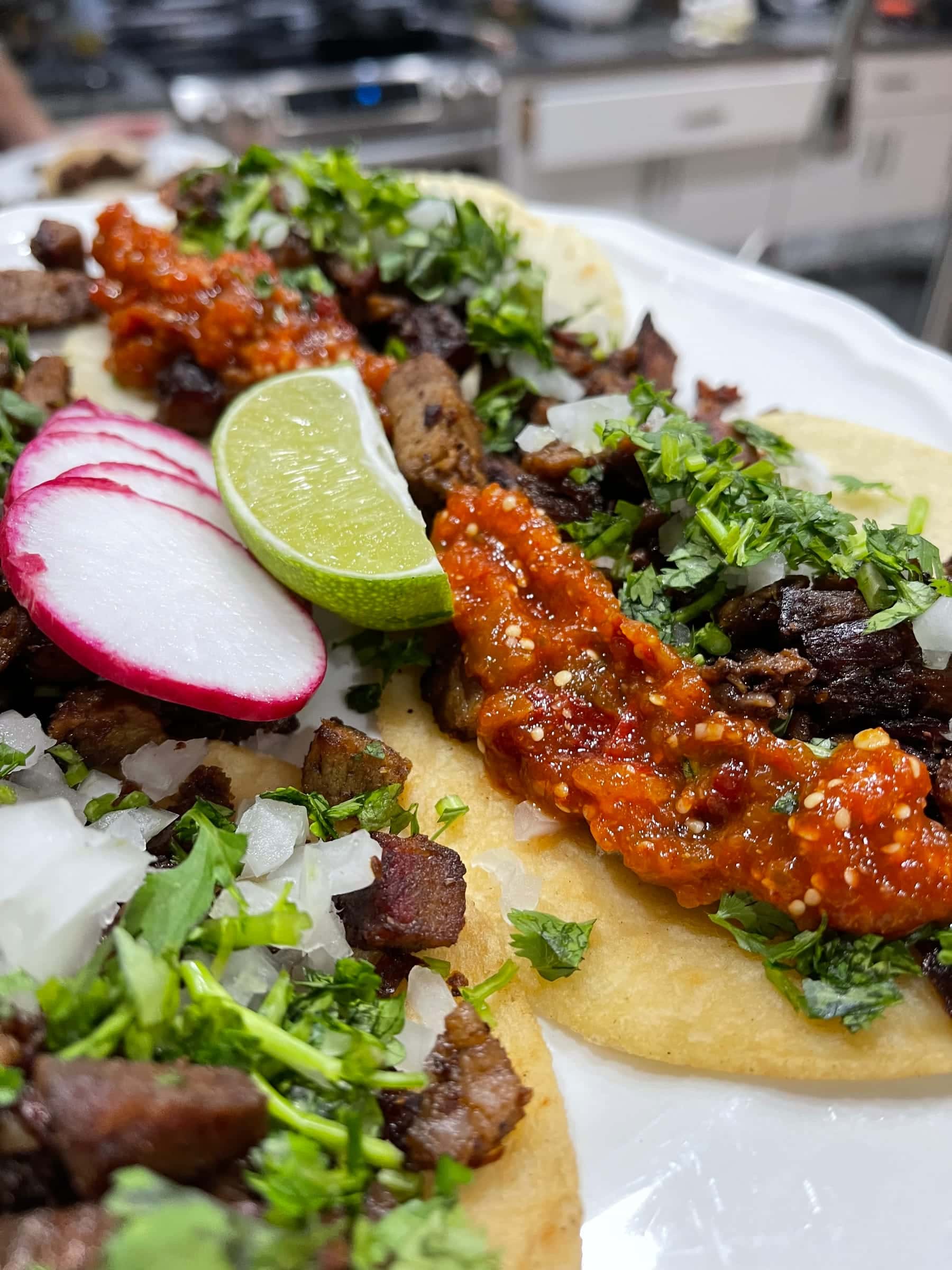 Carne asada street taco with salsa roja, radish, and lime