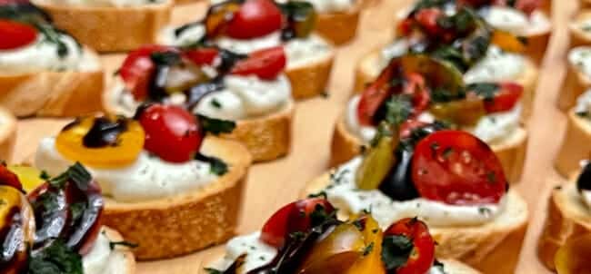 Row of heirloom tomato and whipped ricotta crostini