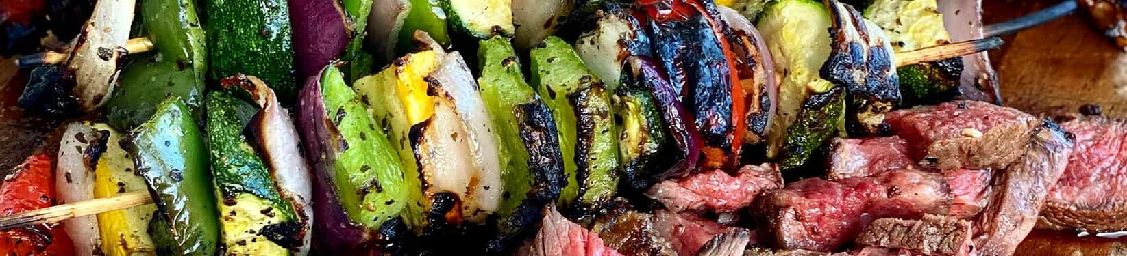 Charred vegetable skewers over sliced steak