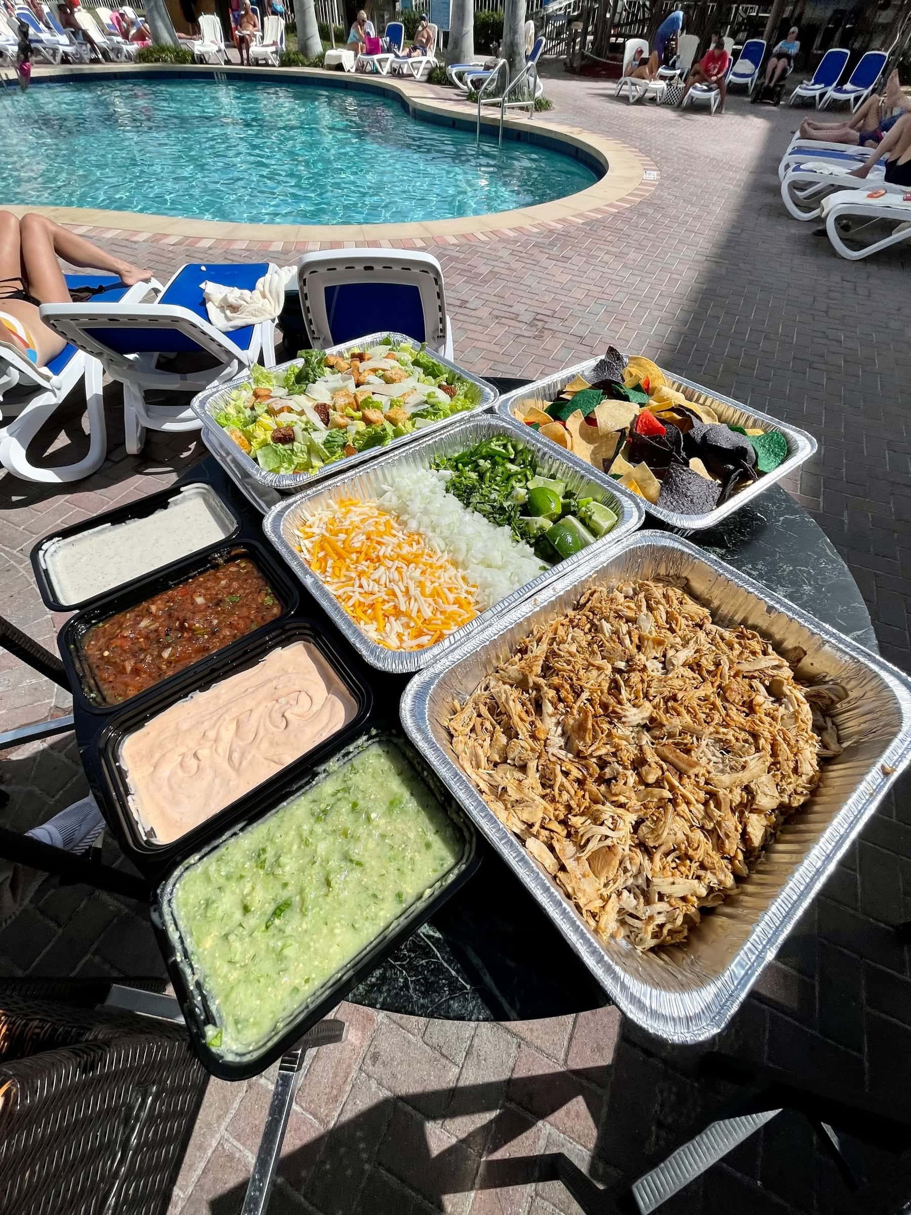 Drop-off catering trays lined up with sides and sauces