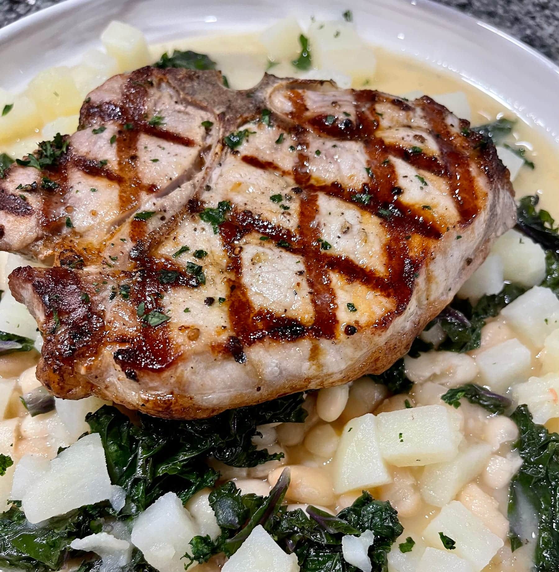 Grilled pork chop over greens and white beans