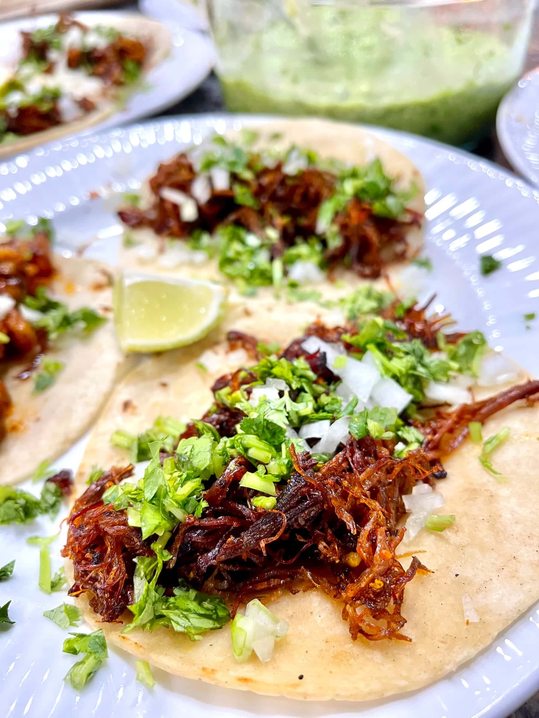 Pulled pork tacos with salsa verde, onion, and lime