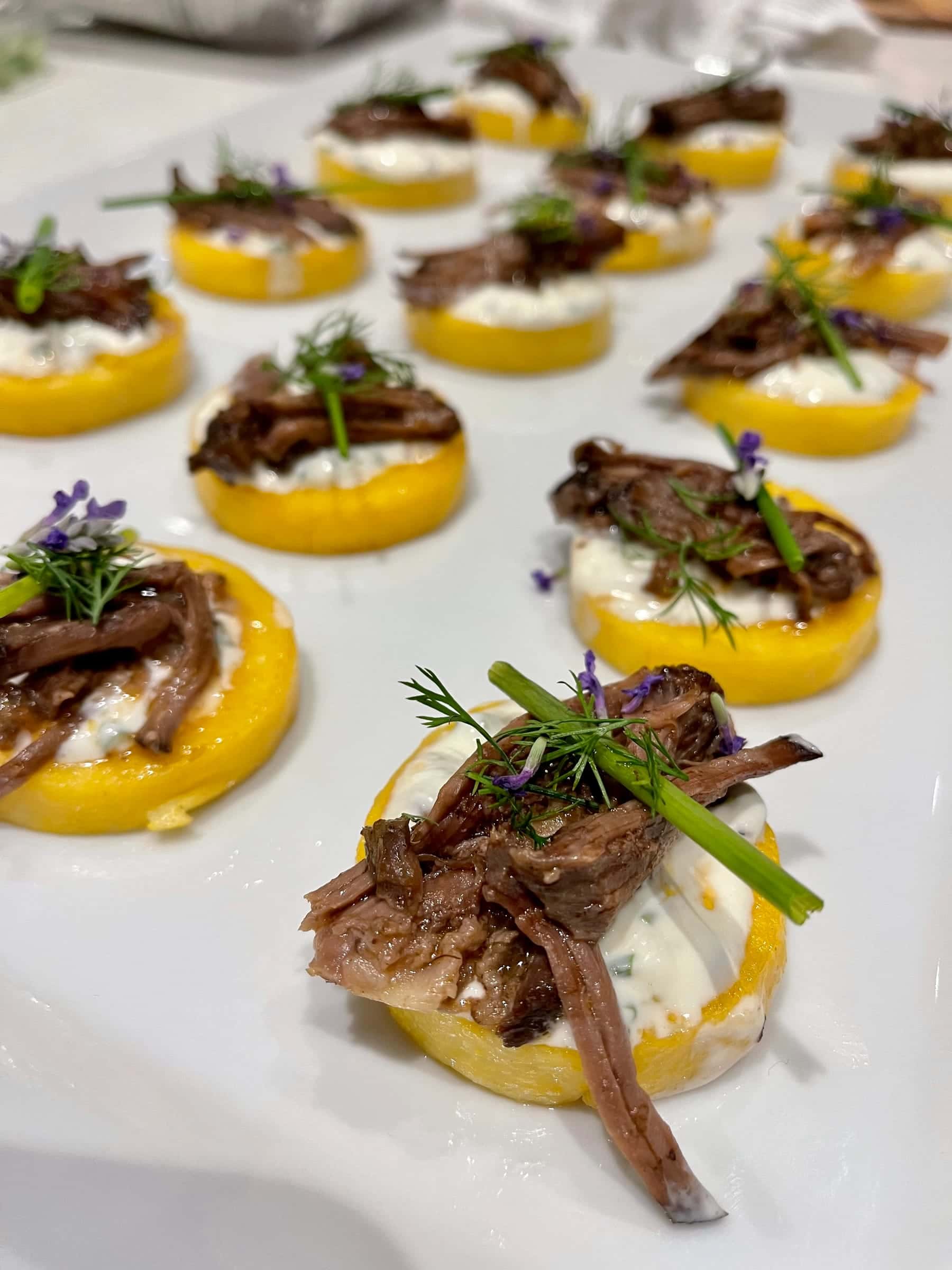 Braised short rib on polenta rounds with chive and flowers